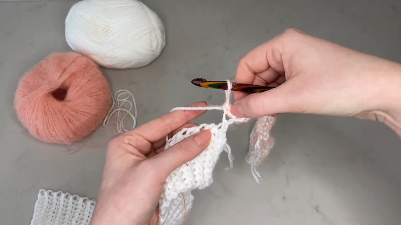 Adding peach mohair yarn alongside the white strand.