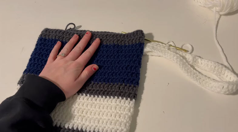 Crocheting a white section onto the striped panel.