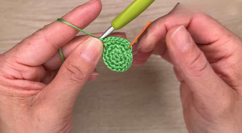 Finished green circle with orange needle threaded through