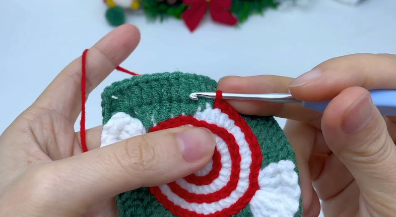 Peppermint front of the crochet Christmas candy pouch with wrapper ends.