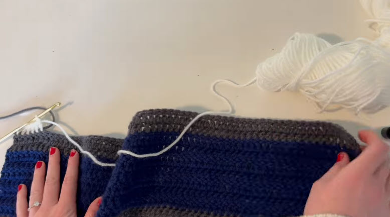 Joining white yarn along the grey edge of the crochet sweater panel.