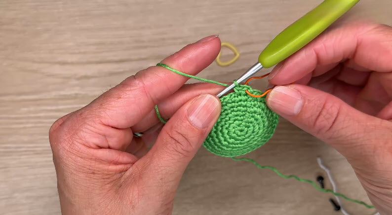Joining orange thread into green amigurumi base
