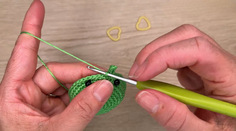 Two green crochet pieces with black safety eyes
