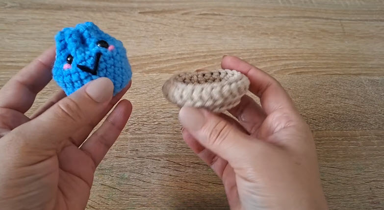 Embroidering a smile and pink cheeks on a crochet dumpling keychain