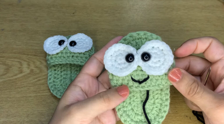 Finished crochet frog baby slipper with eyes and a stitched smile