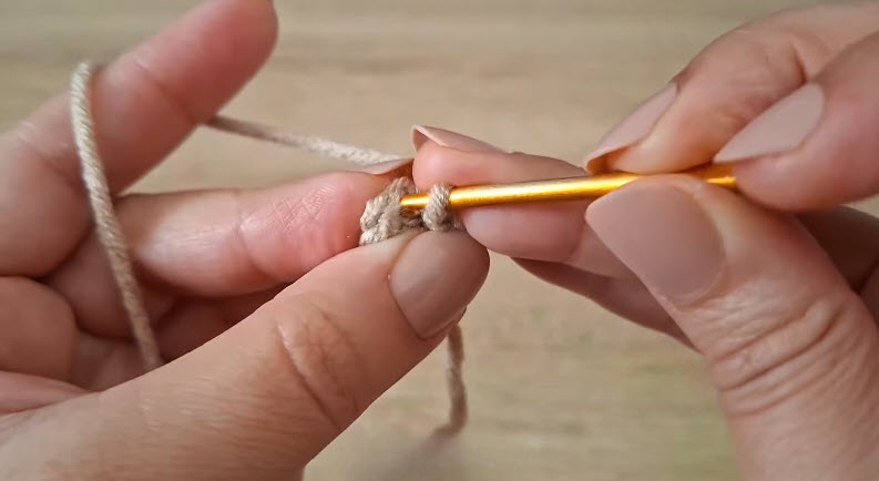 Starting a crochet dumpling keychain with a magic ring in beige yarn